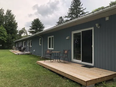Vue extérieure du motel montrant des terrasses en bois avec chaises et tables.